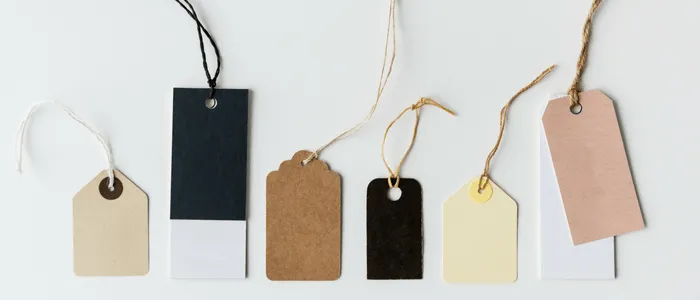 Six blank paper luggage tags on strings laid out in a row, a stand-in for tagging cloud resources